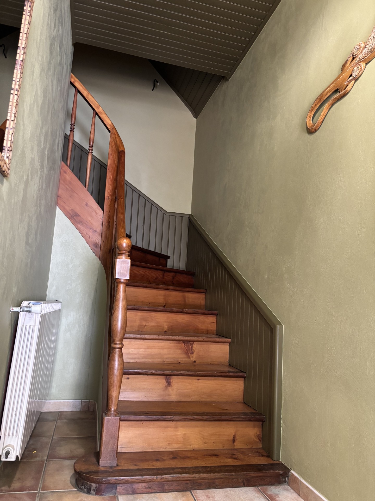 Cage d'escalier rénovée avec murs verts et boiseries assorties